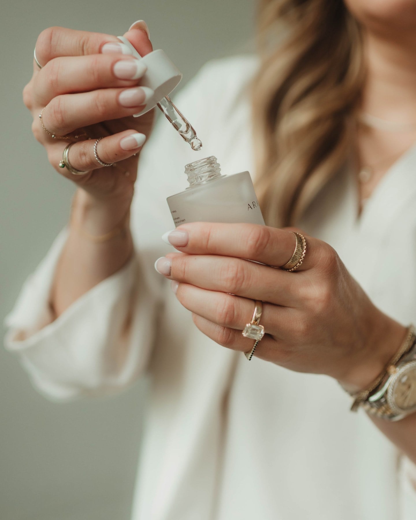 A hand holding the Arkyn Firming and Hydrating Serum dropper