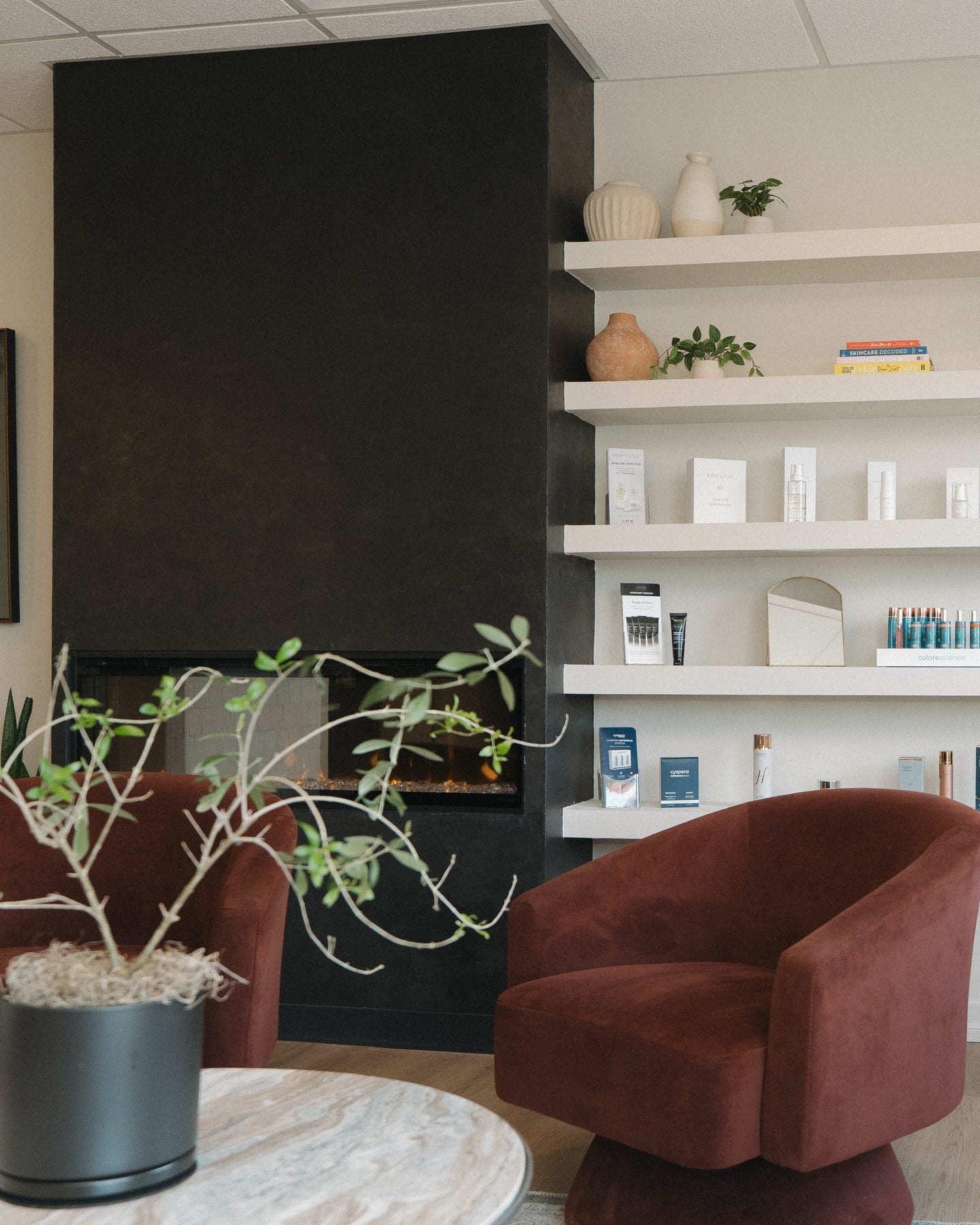 The waiting area inside Illumatox Aesthetic Studio in Neenah, with velvet chairs and the medical-grade skincare shelving