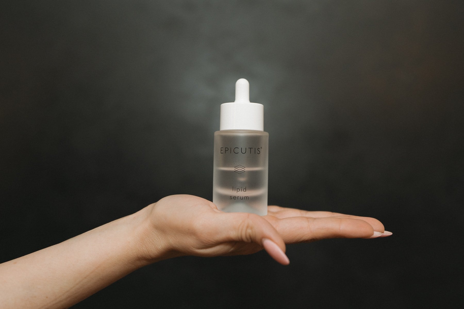 A serum droplet on a hand, photographed against a dark ground at Illumatox in Neenah
