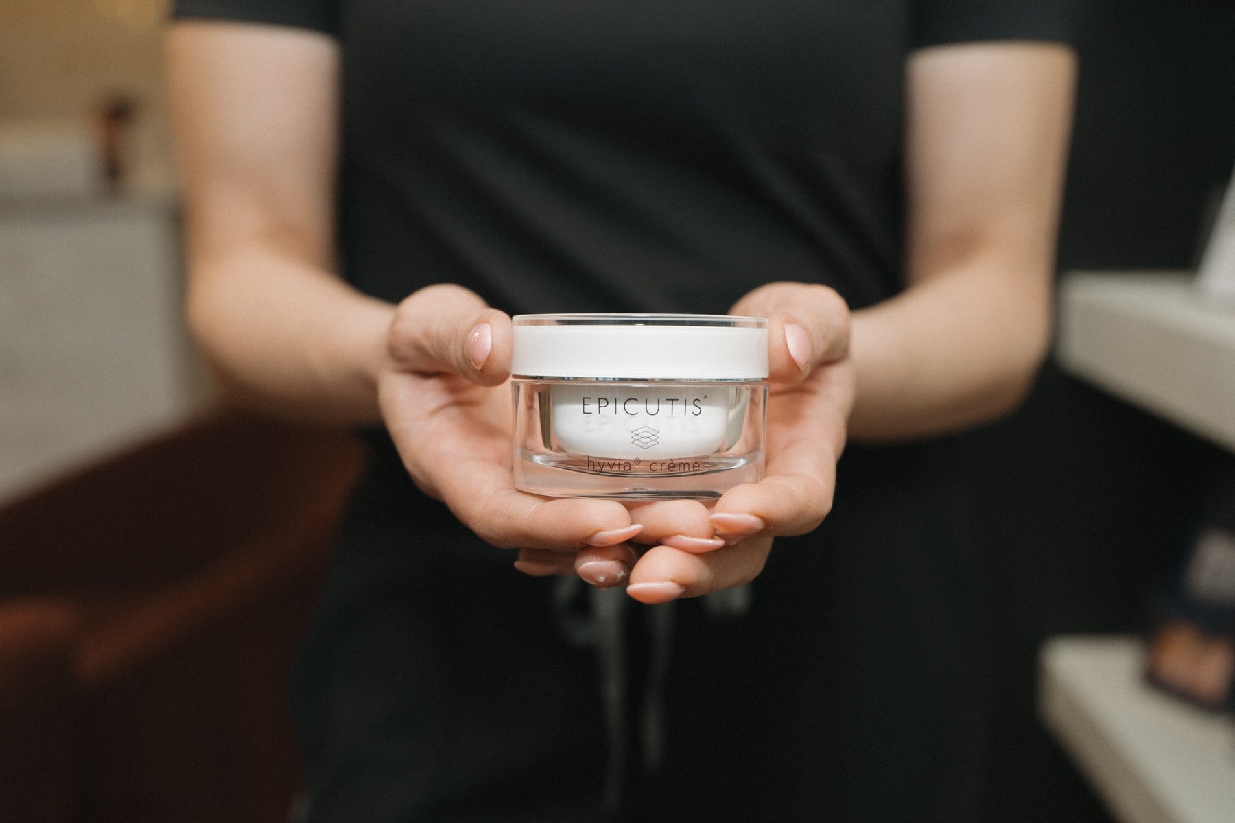A jar of medical-grade skincare held in a provider's hands at Illumatox in Neenah