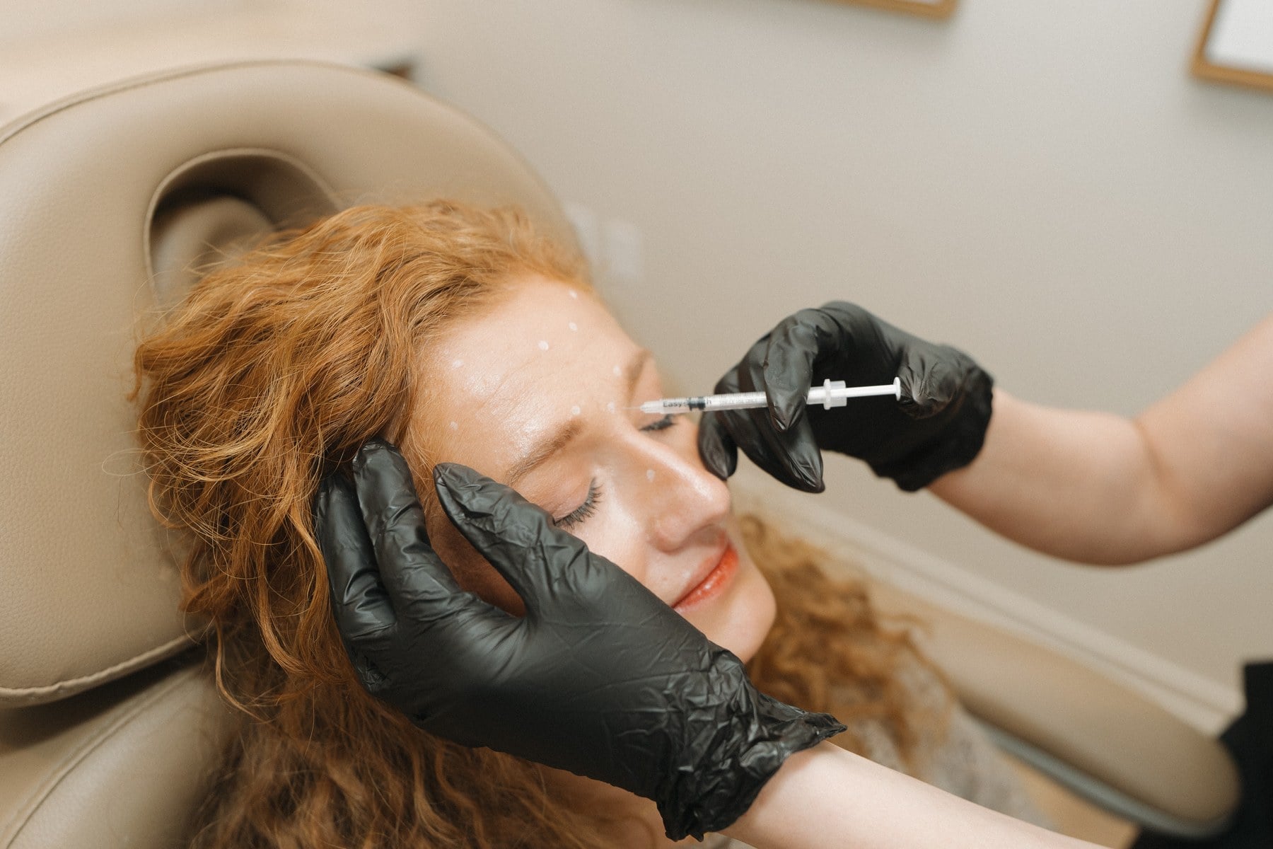A filler syringe positioned against the mid-face of a reclined client at Illumatox in Neenah