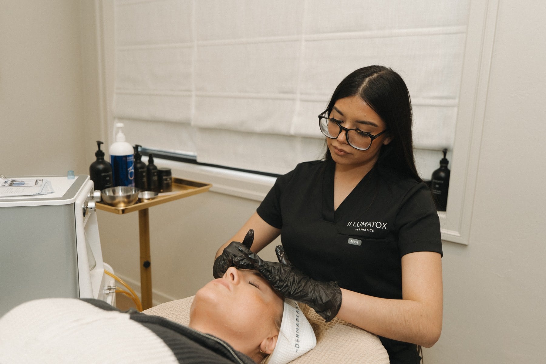 A treatment handpiece being worked across a client's forehead at Illumatox in Neenah