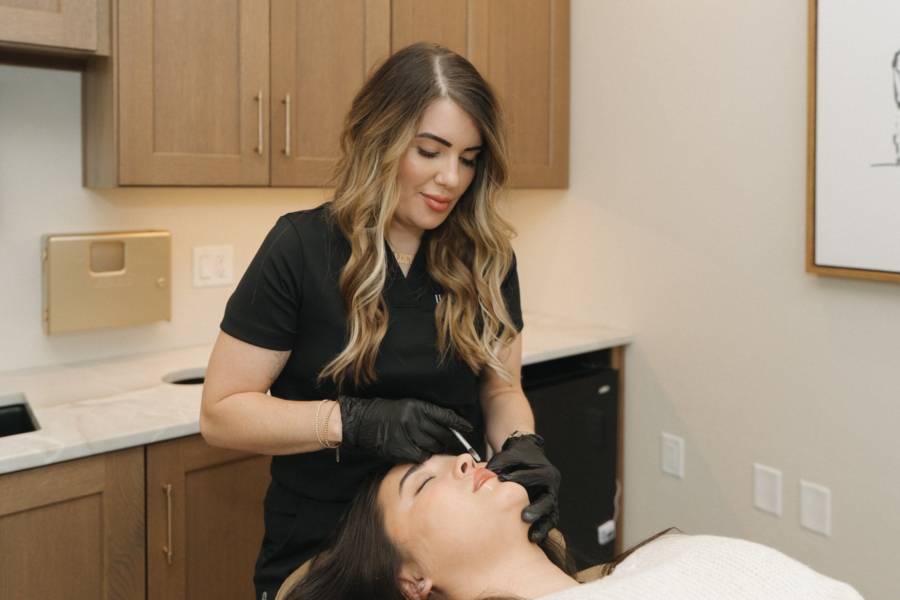 A nurse practitioner preparing an injectable treatment over a reclined client at Illumatox in Neenah