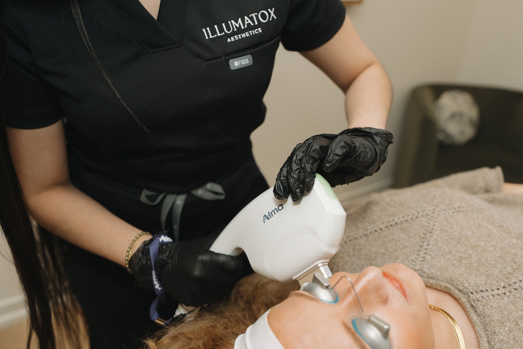 A provider in protective eyewear holding a laser handpiece at Illumatox in Neenah