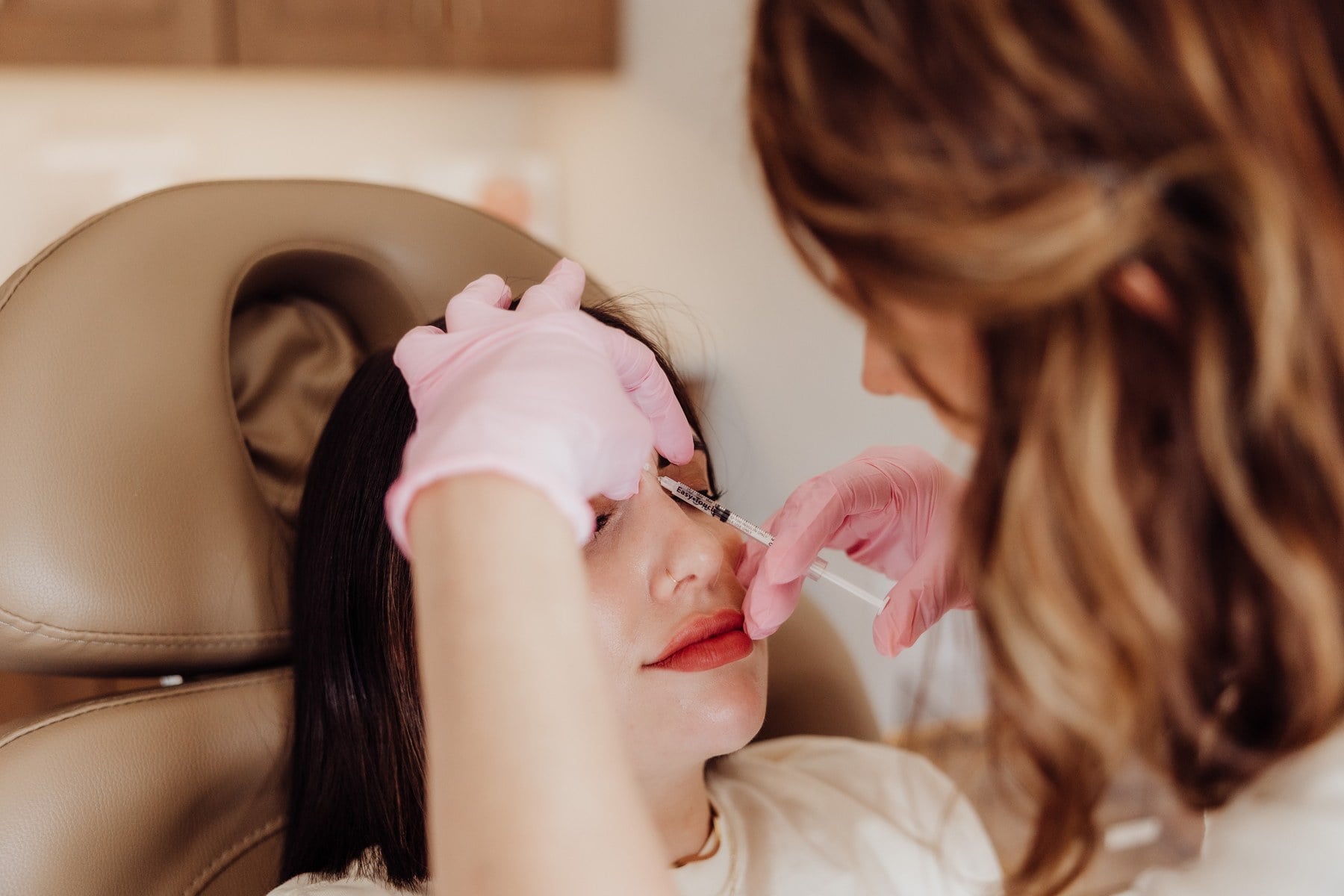 A gloved injector treating a client's upper face during a wrinkle relaxer appointment at Illumatox in Neenah